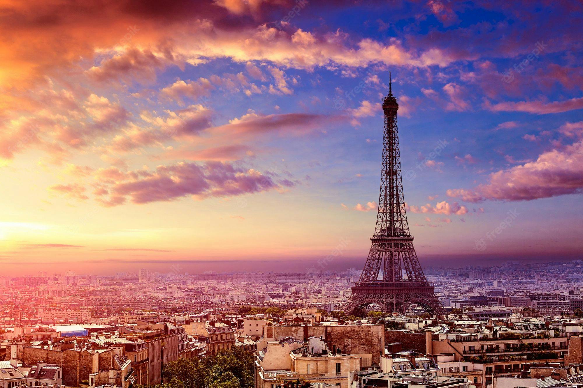 The Eiffel tower surrounded by buildings during sunrise.