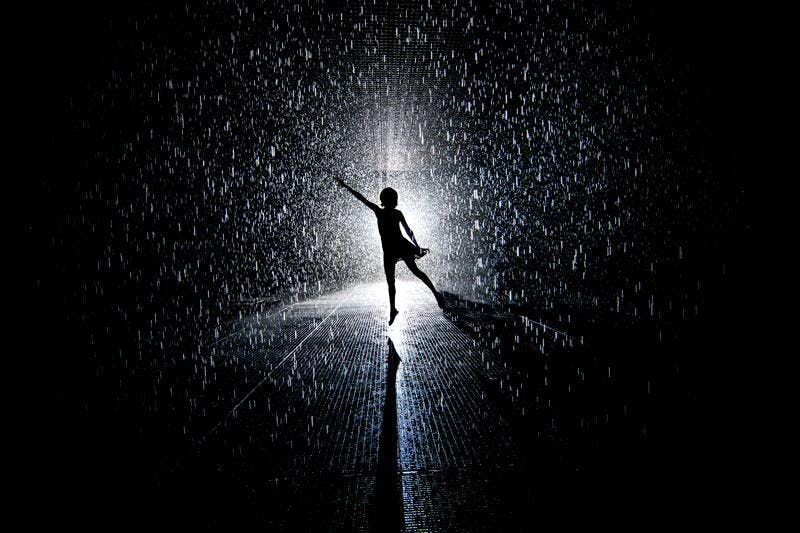 A dark picture of a person dancing in the rain.