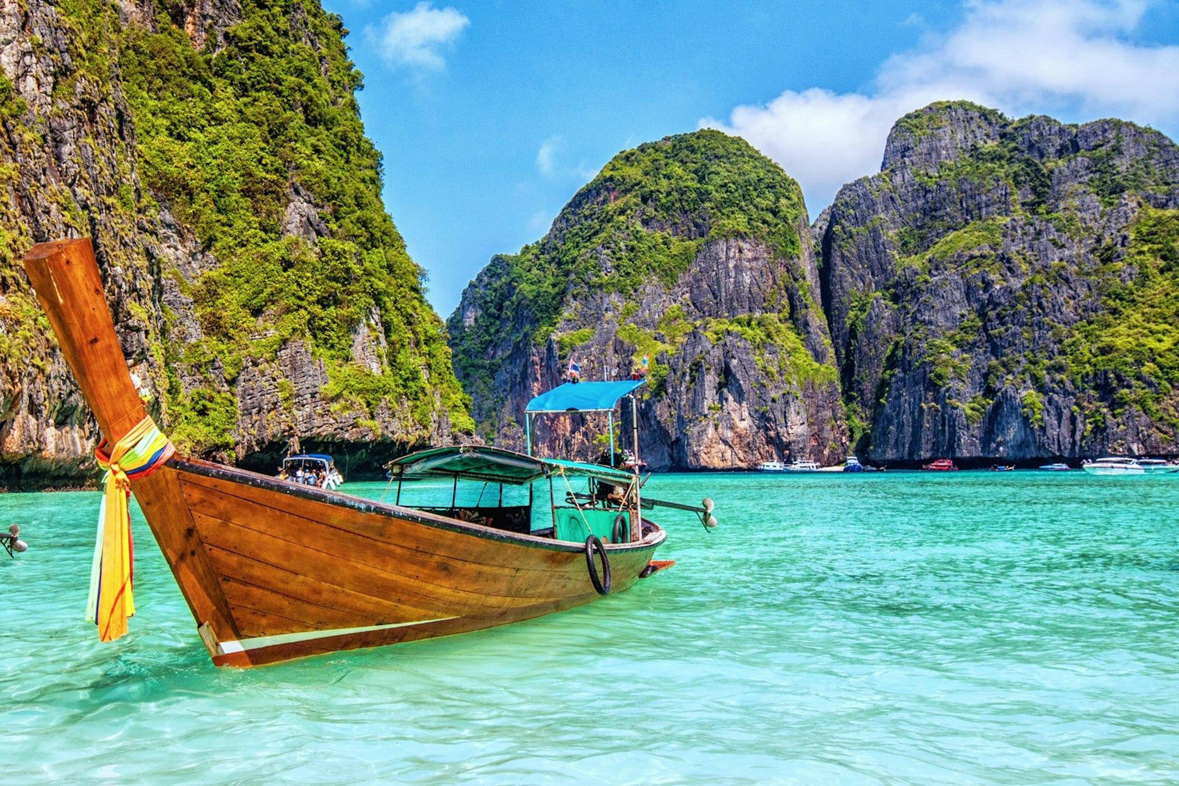 Photo of a boat floating on bright blue water surrounded by mountains.