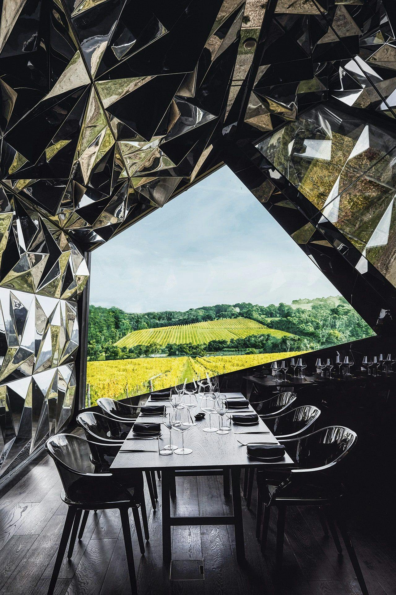A dark set of a table and chairs wih cutlery in a unique shaped room.