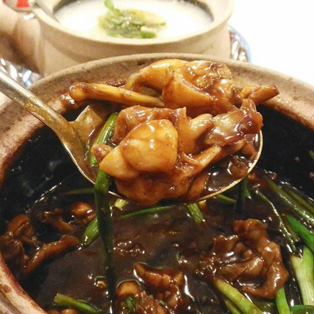 A tasty looking dish with brown broth and rice in a bowl in the background.