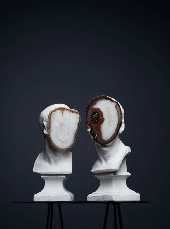 Two white art pieces on a black table with a black background.