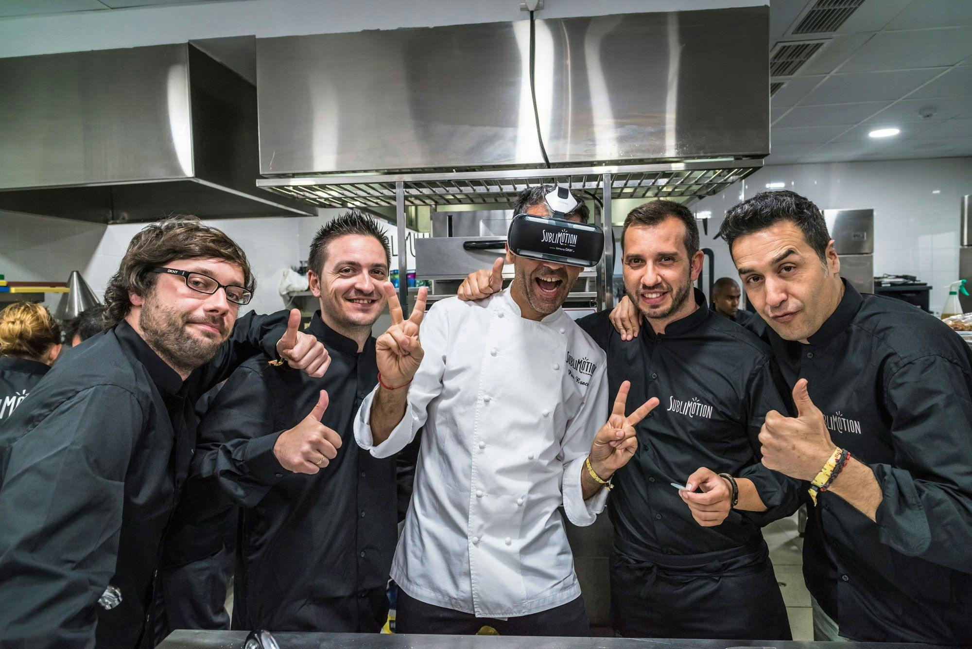 A photo of people inside a kitchen, 4 people wearing black clothes and one person wearing white clothes.