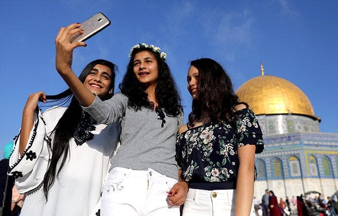 Three women taking a selfie infront of a temple during a sunny day.