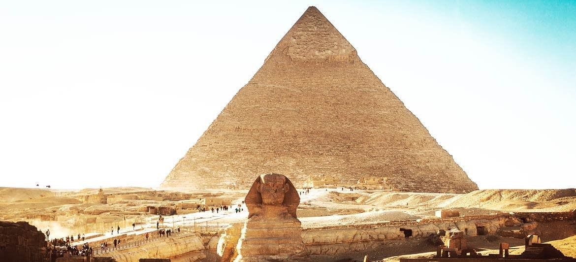 The Sphinx statue infront of a Pyramid.
