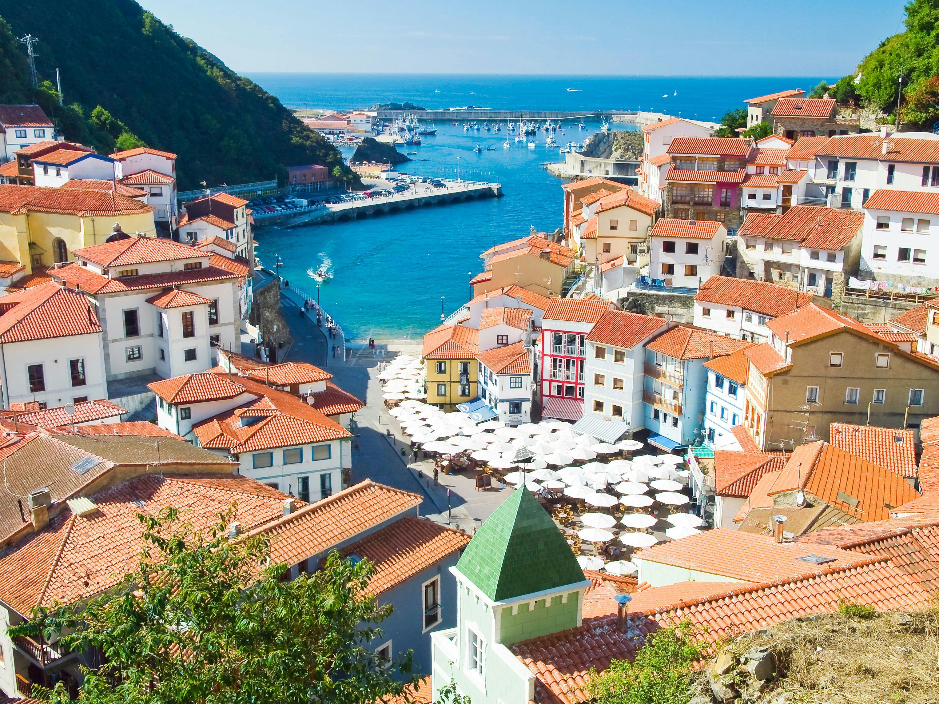 White and brown buildings in between two mountains with a blue ocean view in the middle.