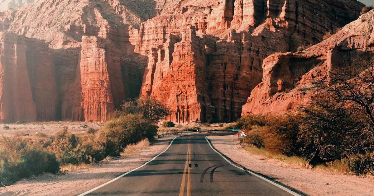 Photo of a road leading between light brown cliffs during daytime