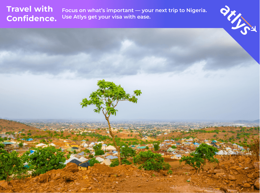 Beautiful greenery can be seen between the dry orange dirt and rocks. It is a cloudy day in Nigeria.
