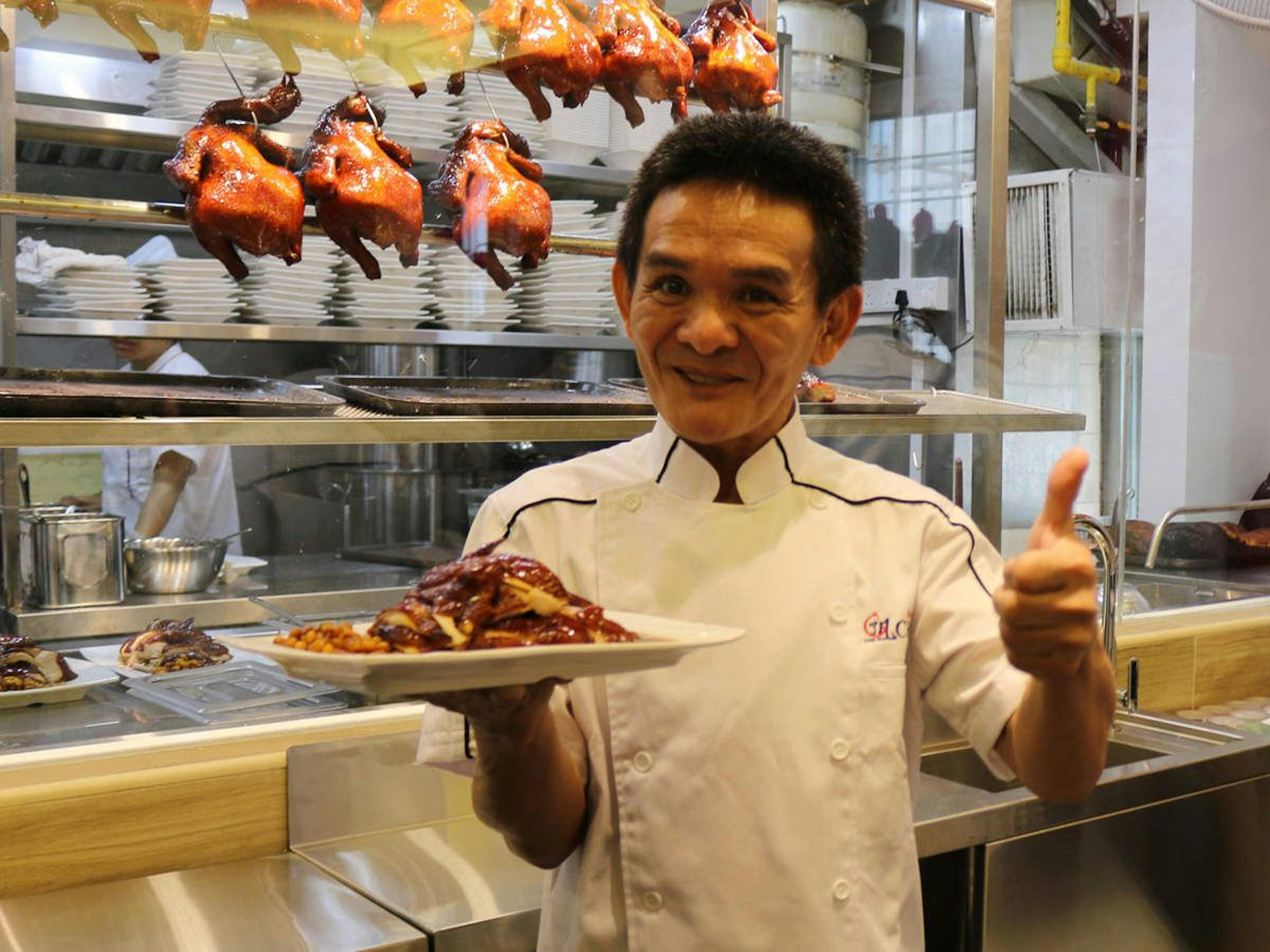 A person holding a plate of food while giving a thumbs up with his other hand.