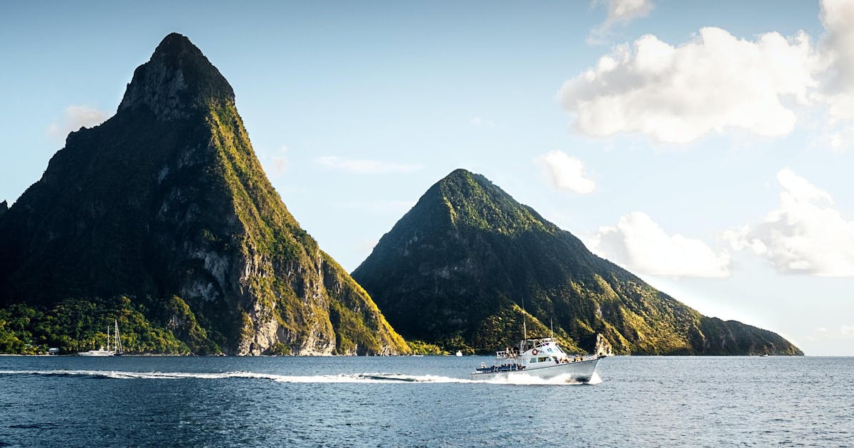 Blue water surrounding green mountains and boats on the water in St Lucia.