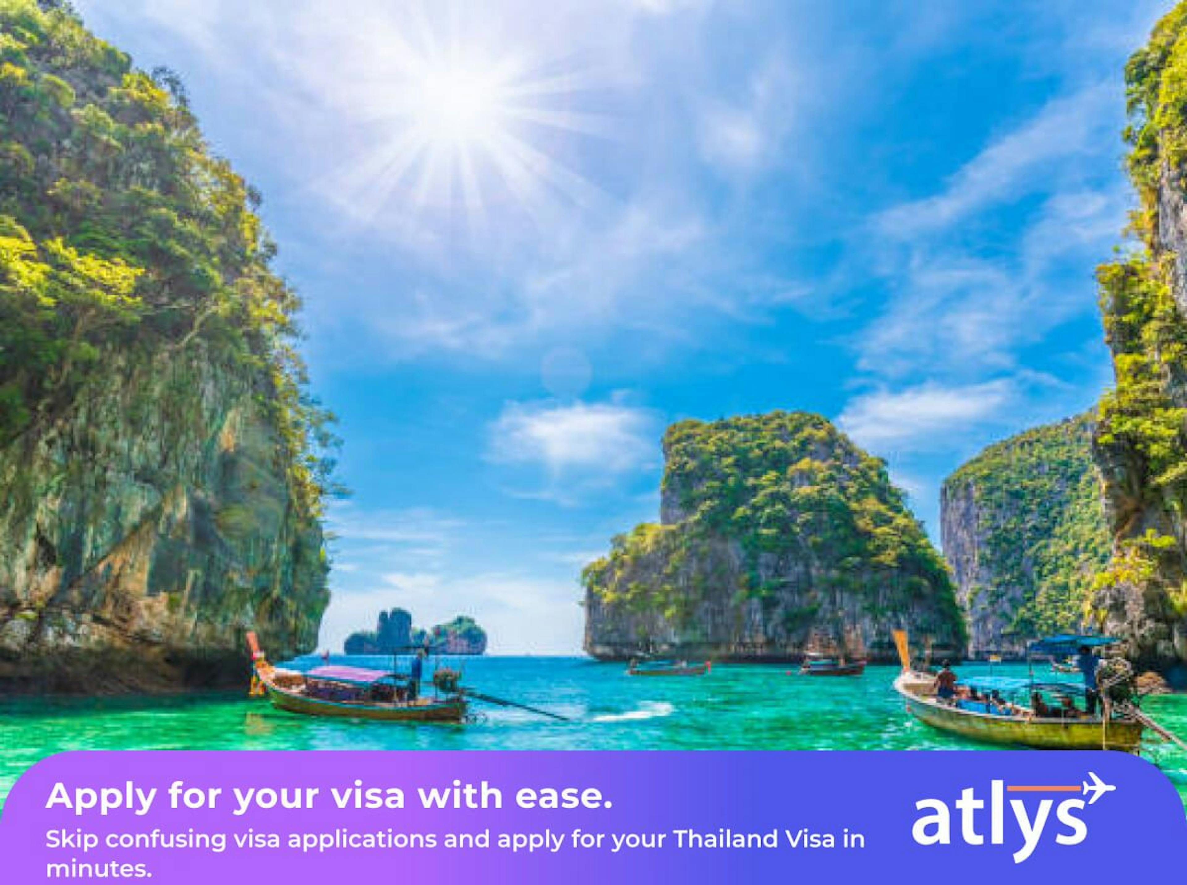 Wooden boats floating in blue water surrounded by rock mountains that is in the water.
