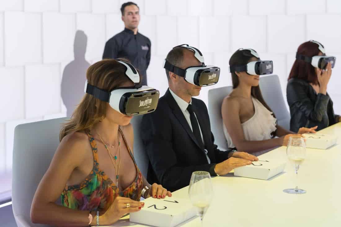 Fou people sitting at a table wearing virtual reality head sets.