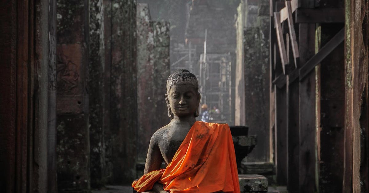 Photo of an old grey statue wearing orange clothes