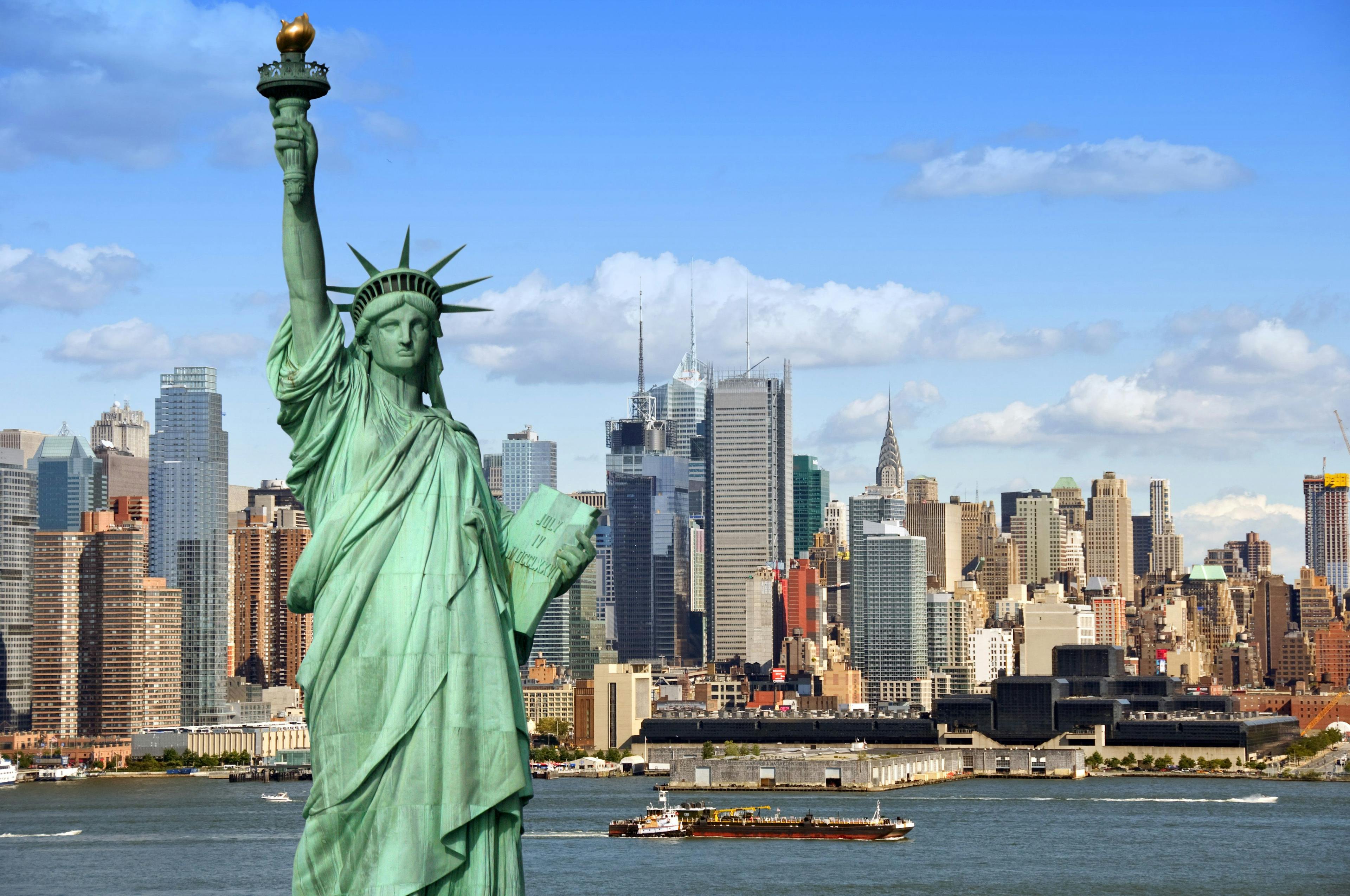 The statue of Liberty with buildings and blue sky in the background.