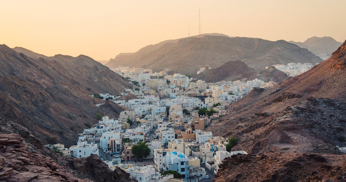 Aerial view of white houses built between two brown mountains during sunset