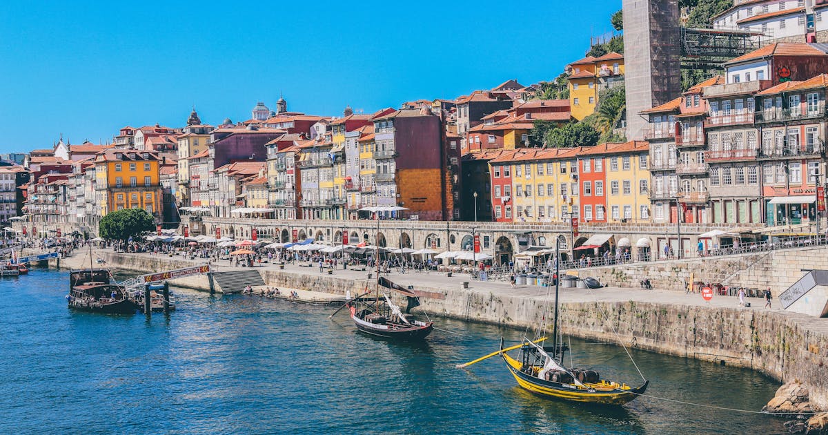 Boats can be seen at the pier in Porto, Portugal. Beautiful colorful buildings can be seen in the background.