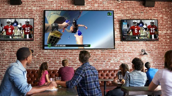 A group of bar goers watching Chive TV on Atmosphere while watching NFL football.
