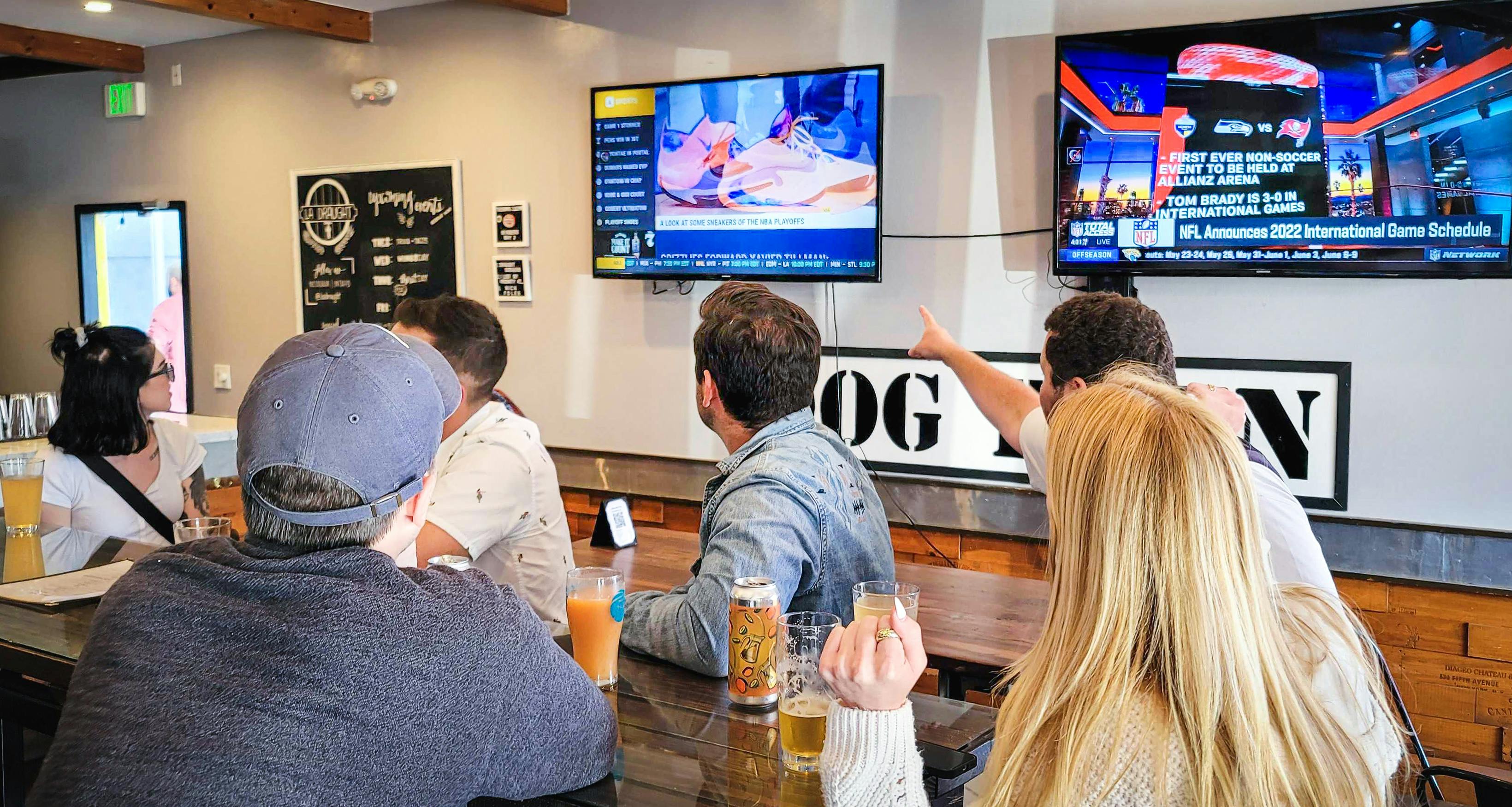 A group of customers sitting at a restaurant watching Atmosphere TV.  
