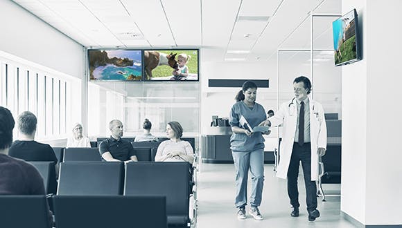 A medical waiting room with patients watching Atmosphere TV waiting for their appointments.