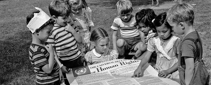 Children gathered around The Universal Declaration of Human Rights document