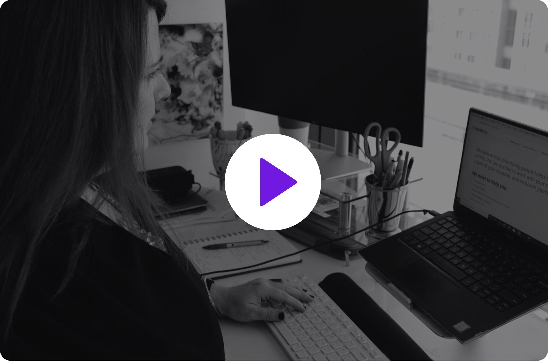 Video thumbnail of a woman sitting at a computer with a play button on top of the image