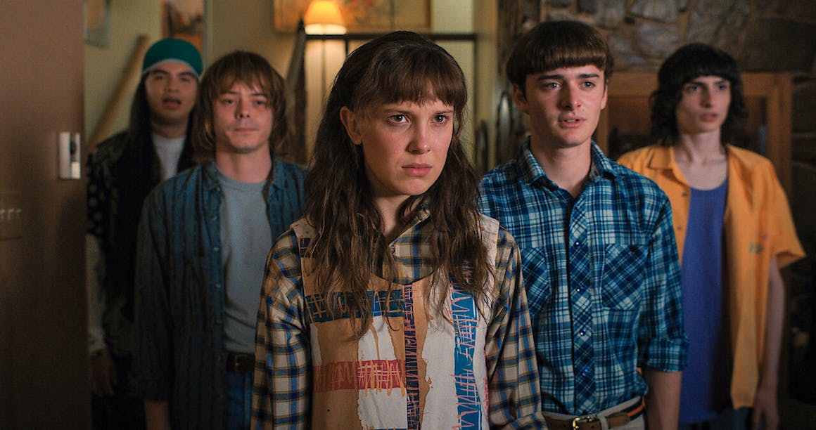A screenshot from Season 4 of Stranger Things, with five of the characters standing inside a house looking past the camera. Credit to Netflix.