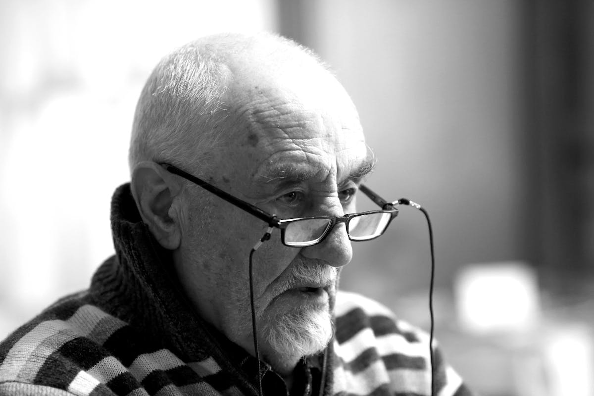 Older caucasian man with black glasses sitting on the ridge of his nose