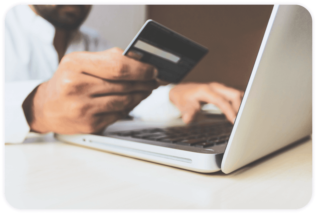 man with brown skin holding a credit card and typing on his laptop