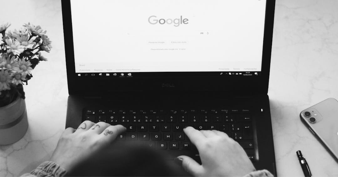 A person typing on a laptop with Google open on the screen