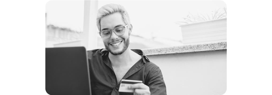 Man wearing glasses sitting a laptop and holding a credit card