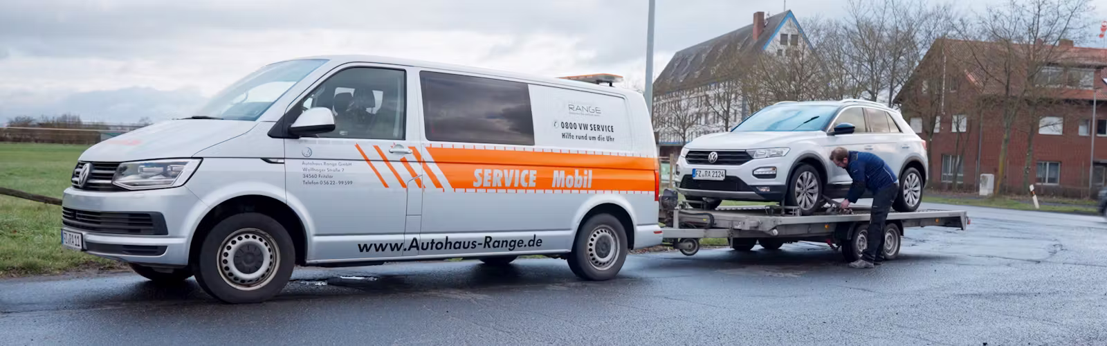 Autohaus Range Service-Mobil-Bus mit Anhänger schleppt einen T-Roc ab.