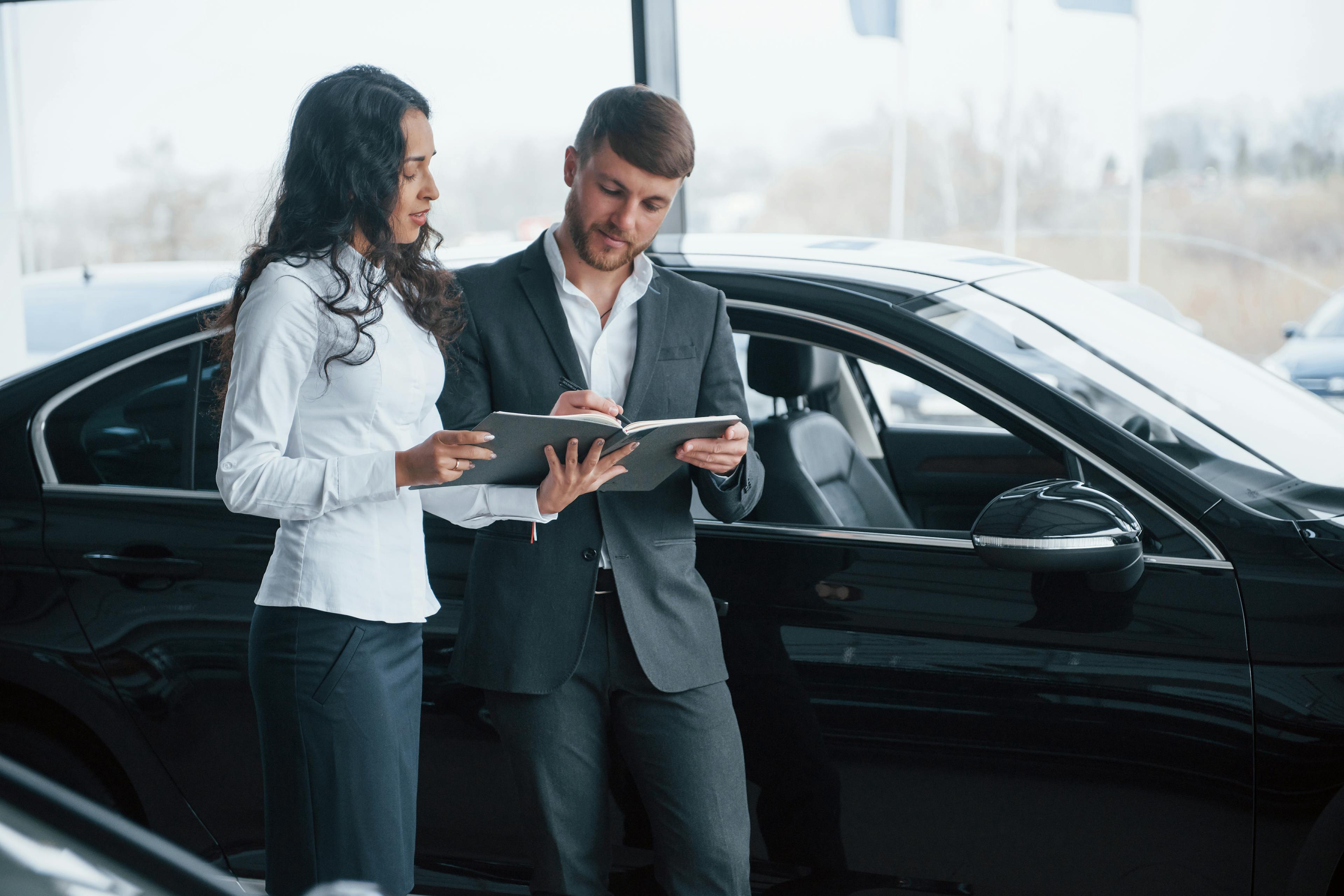 Female Customer Signing Documents of a Male Businessman in Front of a Car