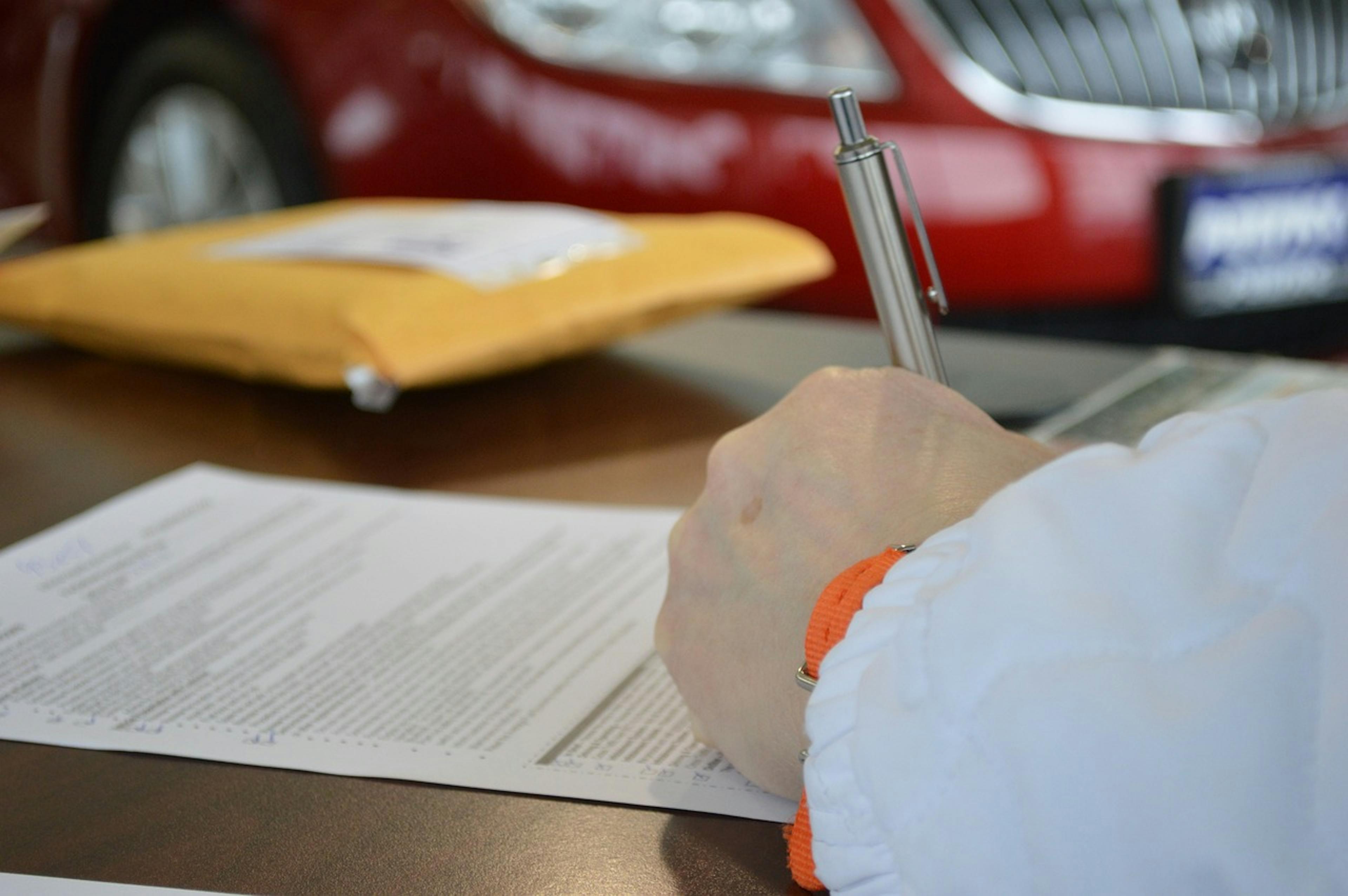 The contract is being signed by a man in front of a car