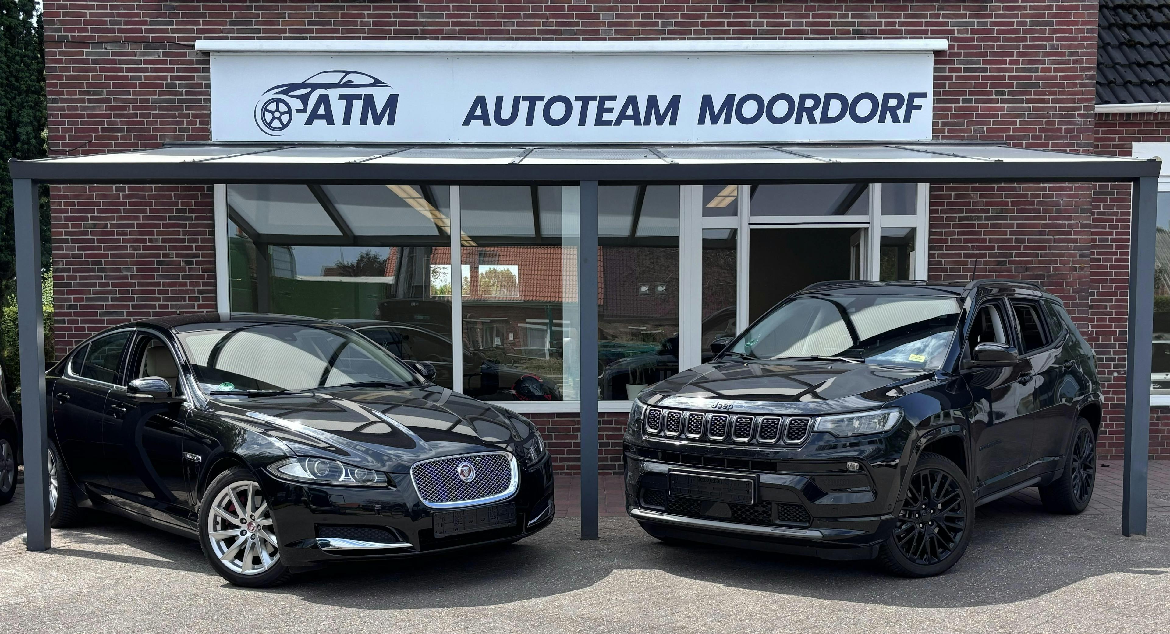 Zwei Schwarze Autos stehen vor dem ATM Laden