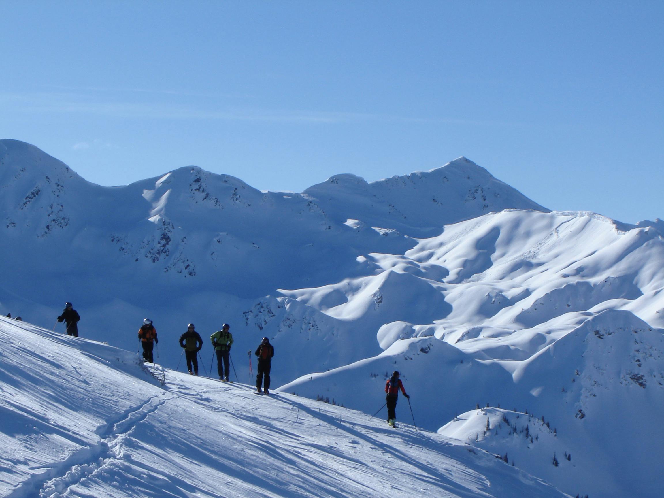 A group of stand on an alpine ridge looking at the terrain below them. Photo by Mark Bender