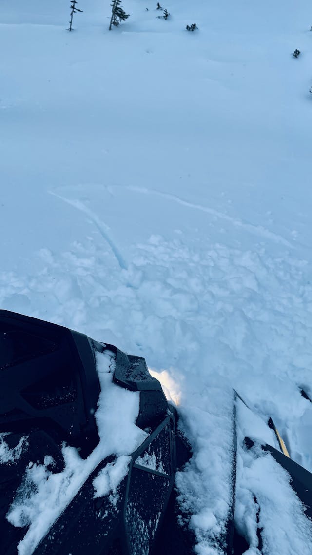 Cracks in the snow surface in front of a snowmobile.