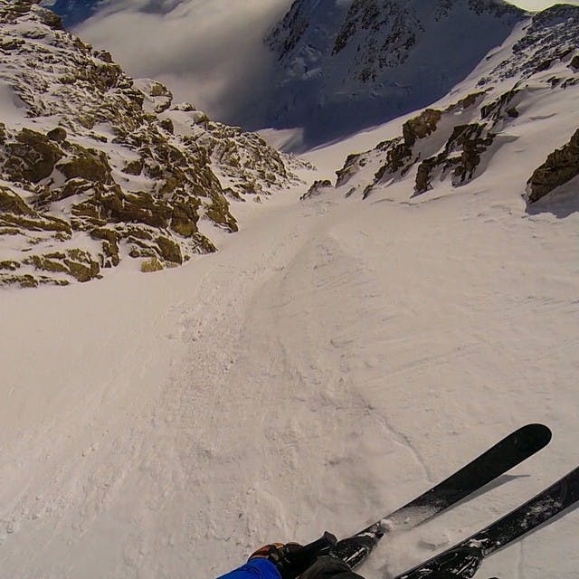 Skier in steep couloir.