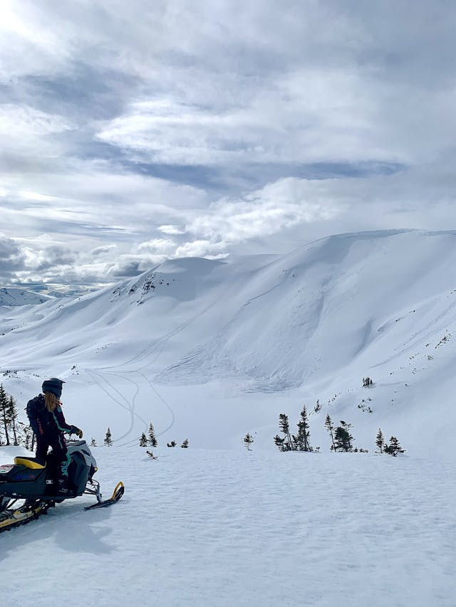 A snowmobiler looks at a large avalanche caused by a cornice failure