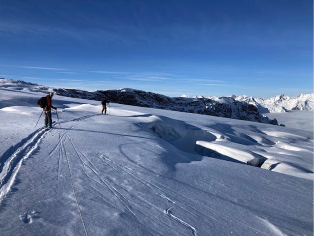 Two skiers on Young's Traverse. The snow cover is thin and features are sparsely covered. 