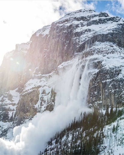 An avalanche spilling over a cliff