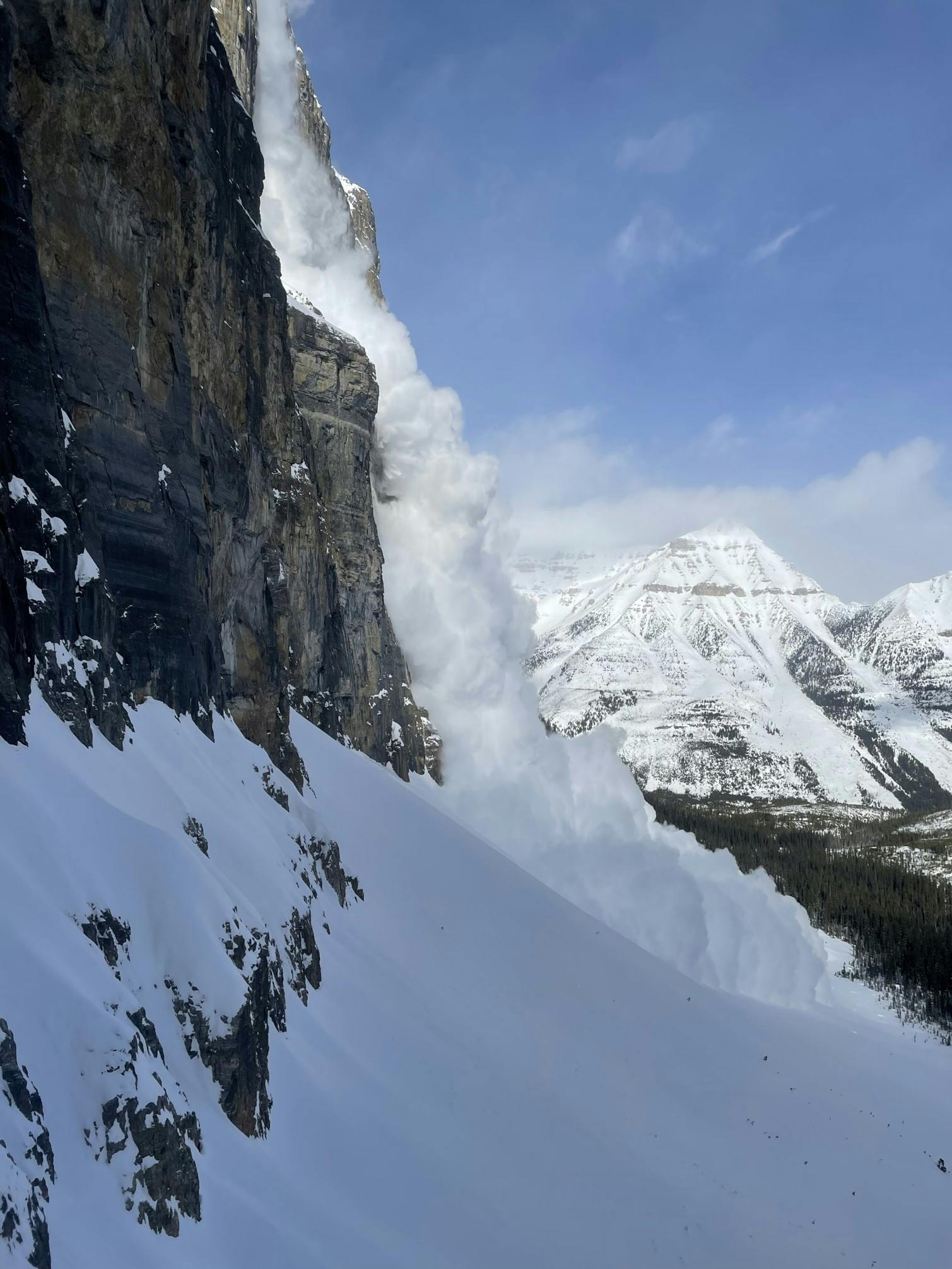 An avalanche coming over the top of a steep rocky face