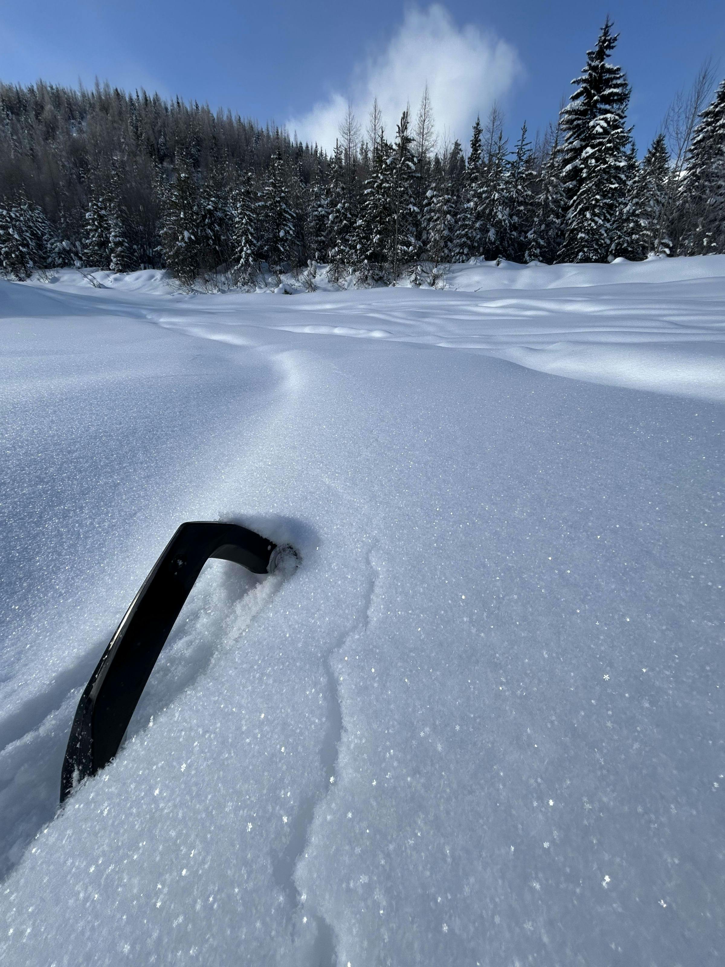 A crack propagates next to a sled ski on flat ground.