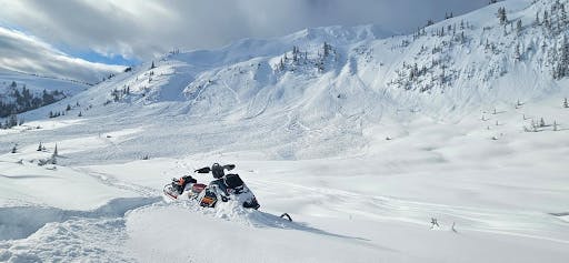 An large avalanche with wide propagation on a fairly short slope. A sled is in the foreground.