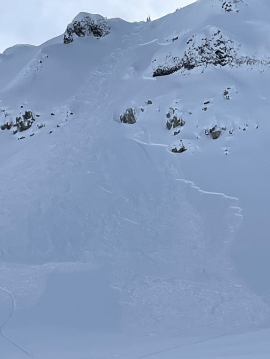 An avalanche in steep terrain with exposed rocky sections