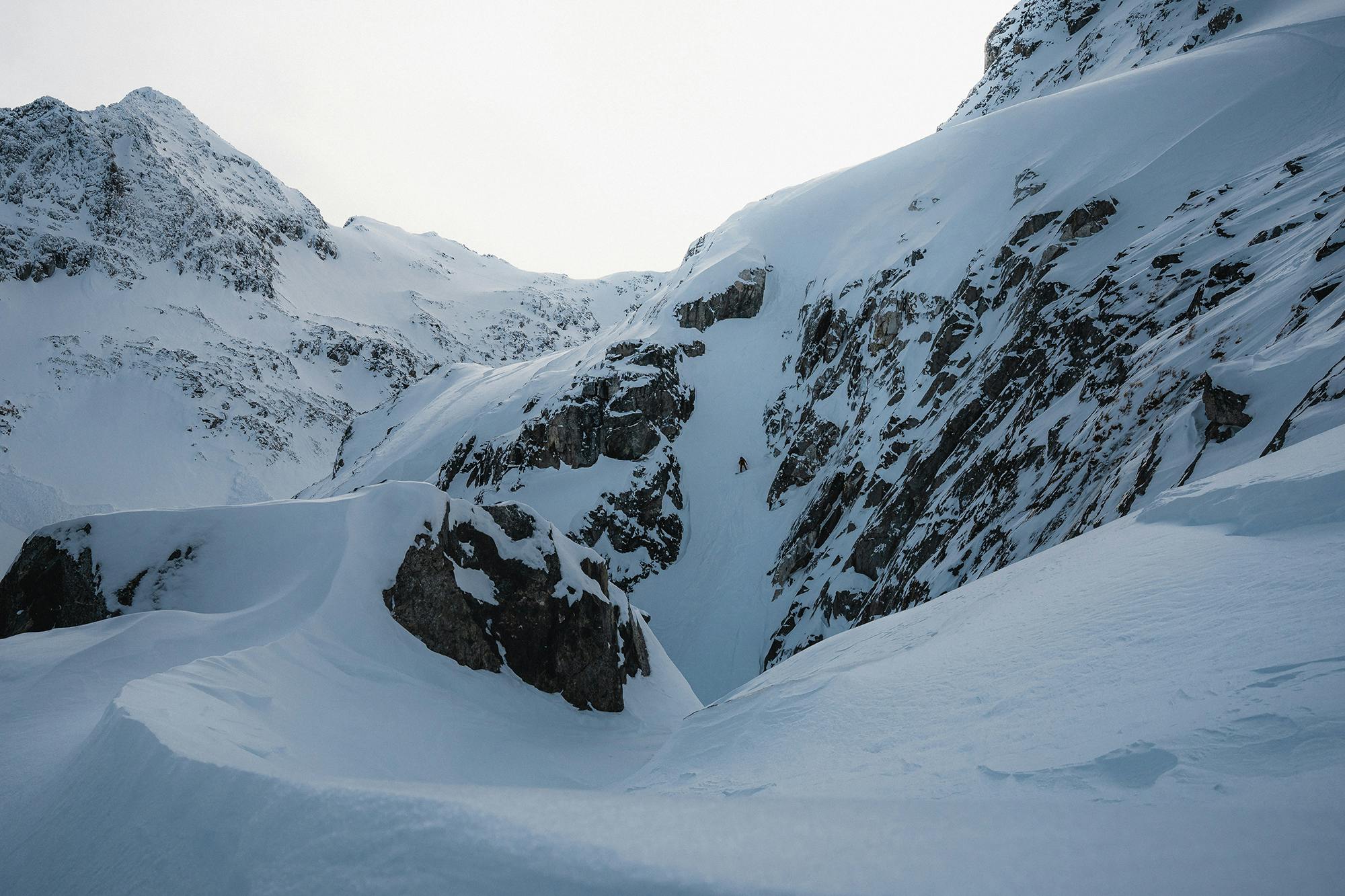 Snowboarder riding in a steep couloir