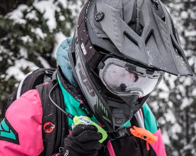 A sledder holds a radio and wears an airbag.