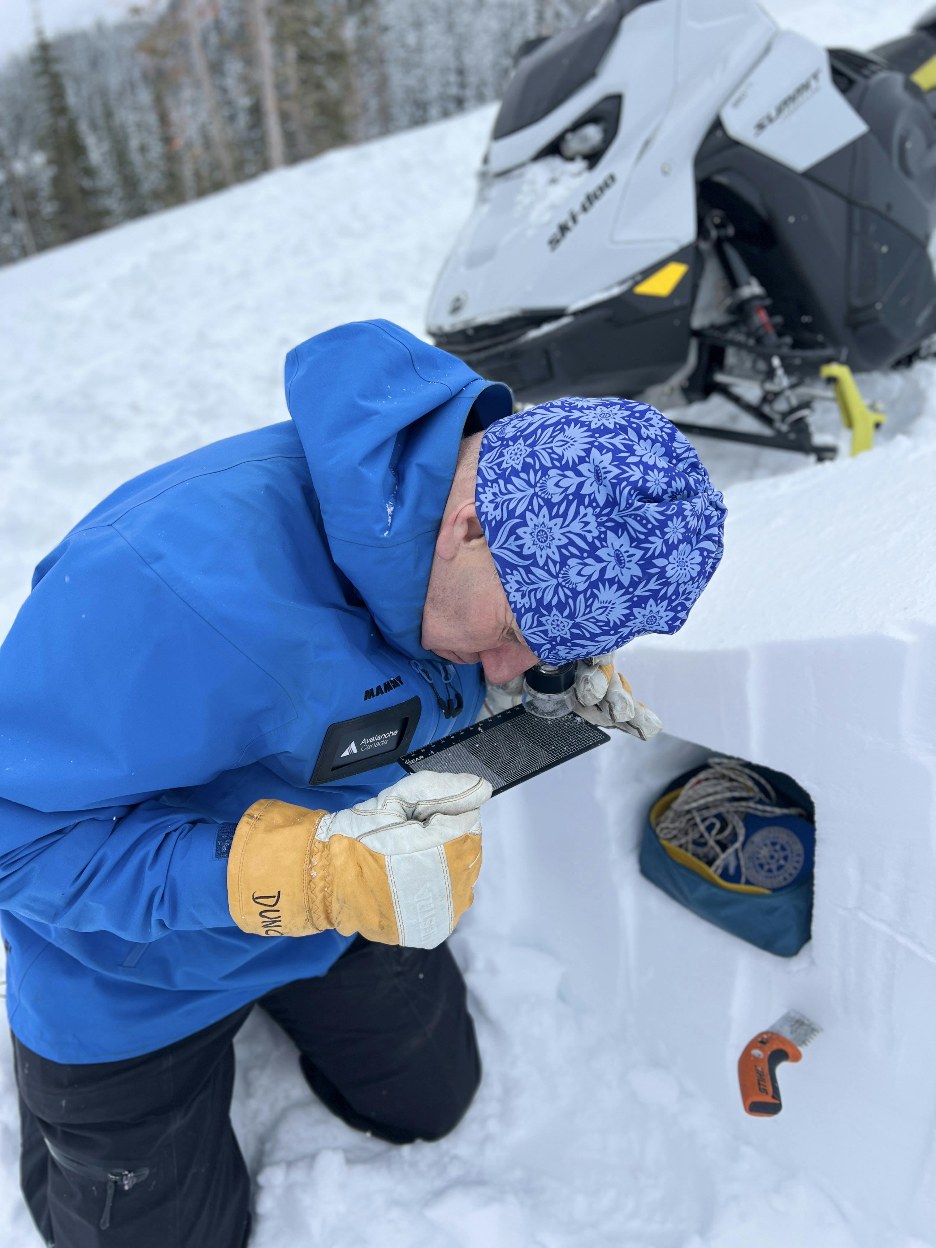 a field technician examines snow crystals on a screen