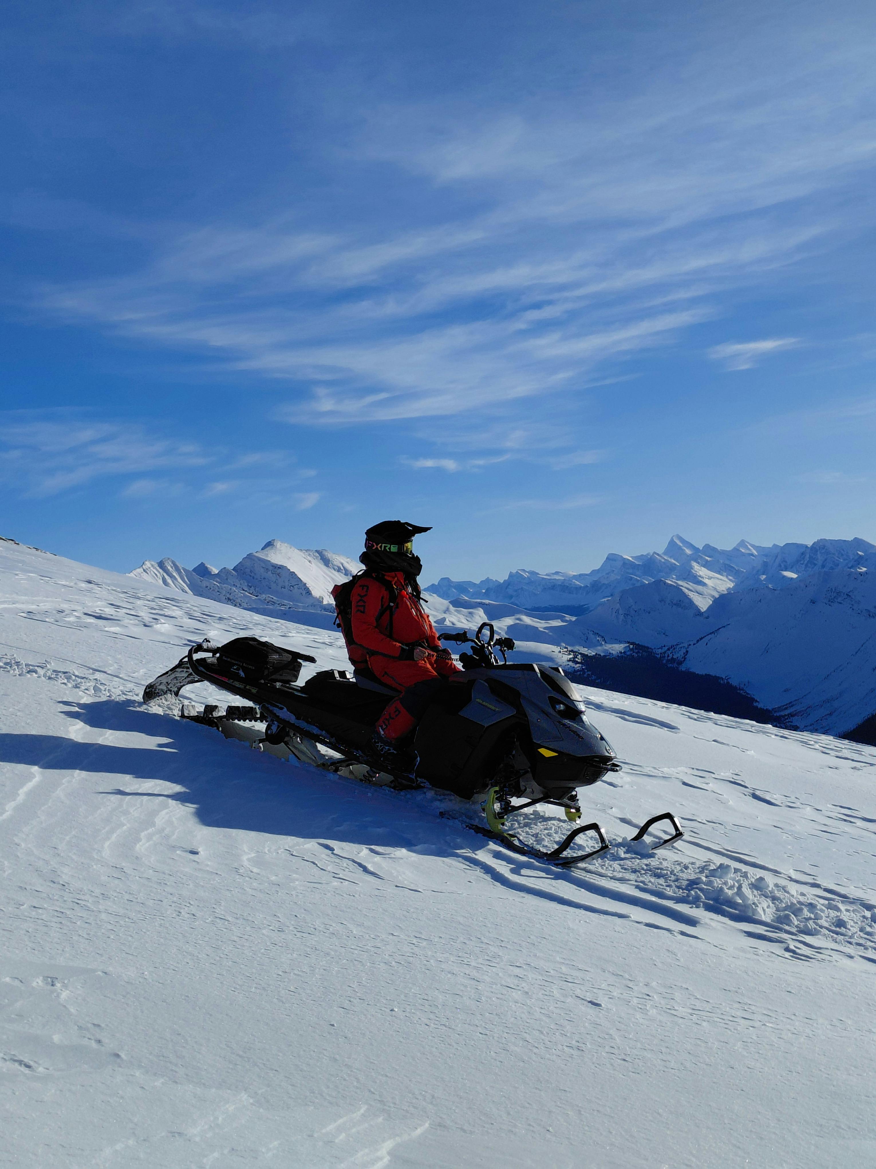 field team member sitting on a Ski-Doo in the sunshine on an alpine slope