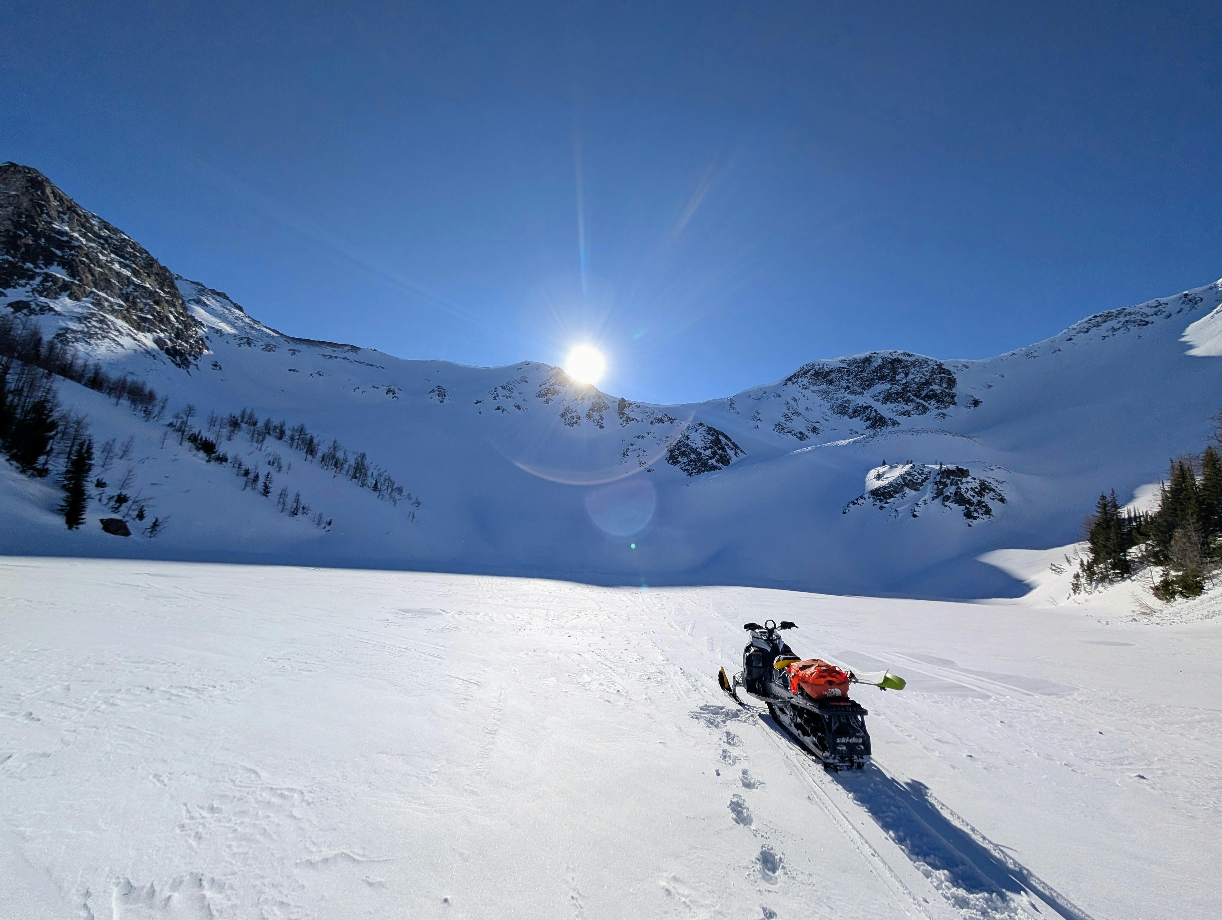 Sled parked on lake under an alpine bowl