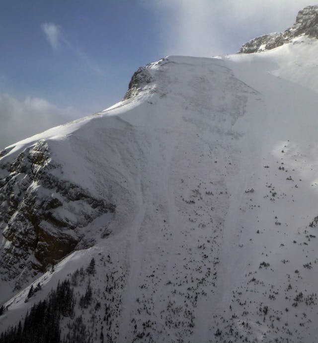 Image shows a large open, rocky mountain face with a large avalanche on it. The avalanche covers almost the entire image and has run to ground in several places. 